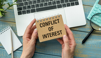 Selective focus of calculator, paper waste, pens and notebook written with text CONFLICT OF INTEREST