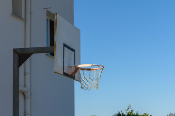 Naklejka premium Urban basketball hoop under a clear blue sky in a sunny afternoon.