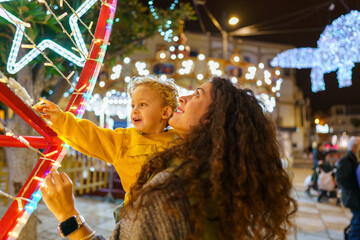 Mother and son admiring christmas lights at night market