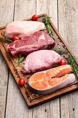 Mix of raw meat and fish . Salmon , beef , pork , chicken staek . Top view