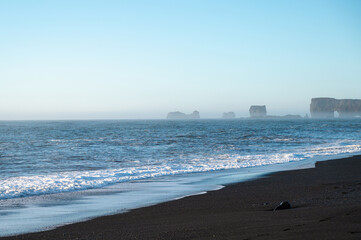 Reynisfjara black sand beach in Iceland. Ocean cliffs. Sunny day. Seascape. Touristic place.