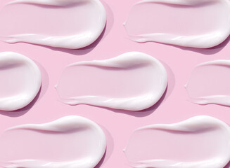 smears of cream texture on pastel pink background