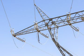 Electricity pylon carrying high voltage power lines on clear blue sky