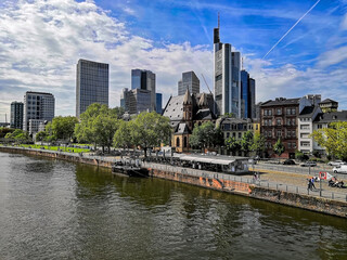 Naklejka premium A stunning view of the Frankfurt waterfront, featuring modern skyscrapers and historic architecture. Great for urban themes, tourism, business, or architectural landscapes.