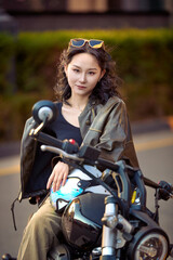 Obraz premium Oriental beauty taking photos on a retro motorcycle at sunset