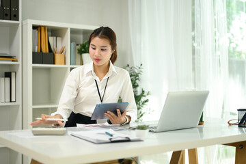 Focused female accountant calculating data and using digital tablet in a office