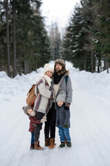 Fototapeta premium Portrait of family standing in the middle of winter snowy nature.
