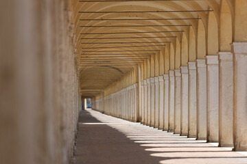 Long covered walkway with columns and arches creating light and shadow