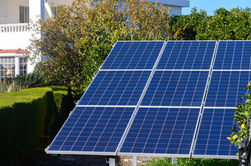 Solar panels gleaming under the sun at a residential garden in a vibrant neighborhood.