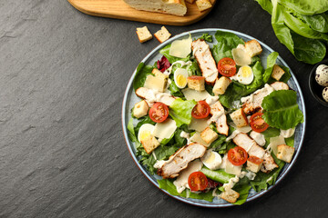 Tasty Caesar salad with chicken and ingredients on dark gray textured table, flat lay. Space for text