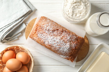 Tasty sponge cake with ingredients on white wooden table, flat lay