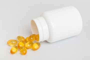 Omega-3 capsules lie in white bottle on a table background. Fish oil tablets top view. Biologically...