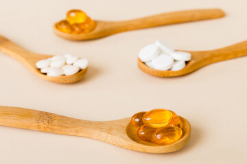 Vitamin capsules in a spoon on a colored background. Pills served as a healthy meal. Red soft gel vitamin supplement capsules on spoon