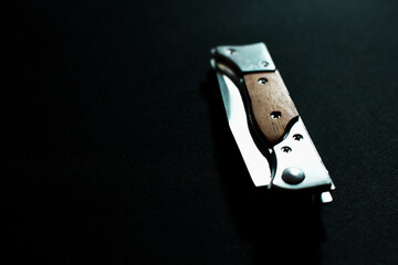 Folding knife with wooden handle on dark background