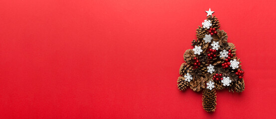 Christmas tree made from natural cones on colored background, view from above. New Year minimal concept with copy space