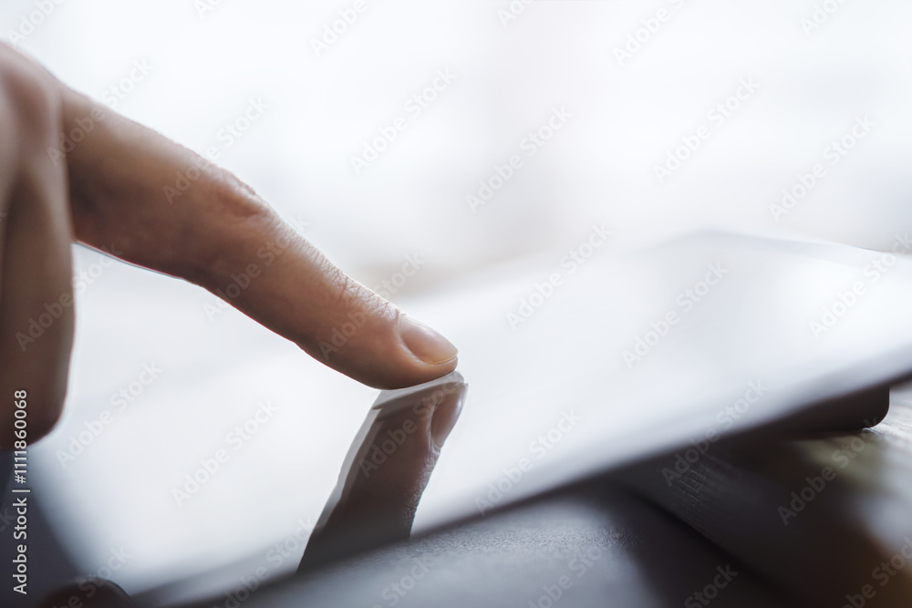 Poster detailed observation of a man's finger navigating the screen of an advanced tablet, device placed on