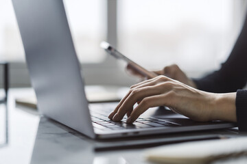 With a softly blurred office scene in the background, the image reveals a close-up of a woman's hands typing on a stylish laptop keyboard