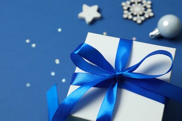 Beautiful gift box tied with bow and Christmas decorations on color background 