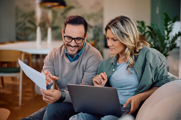 Smiling couple going through their home finances at home.