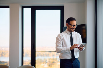 Happy businessman using smart phone in office.