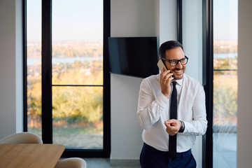 Happy businessman talking on cell phone while working in  office.