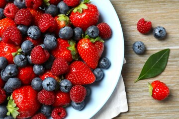Different fresh ripe berries in bowl on the table, top view