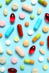 Various medicine pills and capsules on color background 