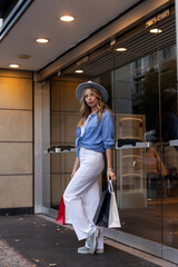 Young woman walking down street with bags after shopping. Shopping in the mall