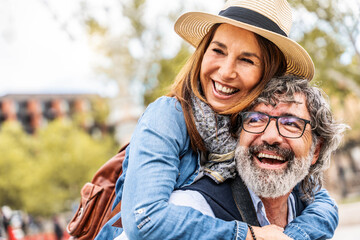 Happy senior couple having fun walking on city street - Two older tourists enjoying together...