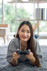 Young asian woman playing console game relax in living room, enjoy leisure weekend at home. Stress...