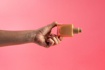 Cosmetic cream tube in womans hand on pink background 