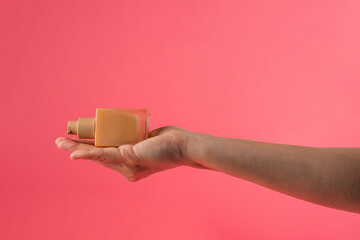 Cosmetic cream tube in womans hand on pink background 