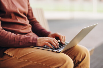 Businessman working using laptop computer, sitting on couch top view, selective focus on hands
