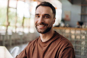 Portrait of happy smiling bearded man looking at camera, sitting in modern cafe. Dental care concept