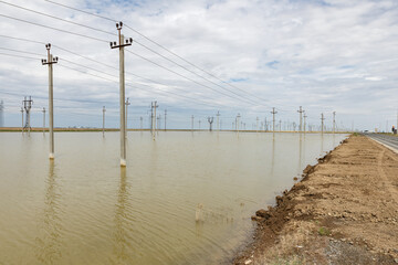 Flooded landscape with power lines standing in water under cloudy sky in rural area