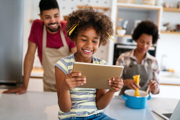 Happy african family having fun with device at home. Black parents and child using digital tablet