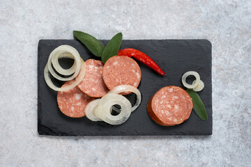 Traditional sliced Czech pickled sausage Utopenec with pepper and onions on a stone background. Top view.