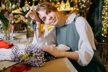 A woman in her florist shop collects bouquets of flowers. The concept of a small business. Bouquets of tulips for the holiday on March 8.
