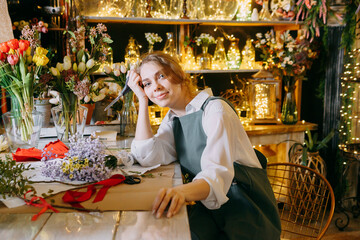 A woman in her florist shop collects bouquets of flowers. The concept of a small business. Bouquets of tulips for the holiday on March 8.