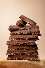 Closeup shot of stacked chocolate bars or turron bars with puffed rice, macro texture, hero shot on wooden podium