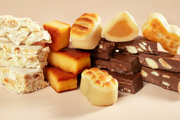 A wooden platter with traditional Spanish Christmas sweets: turron and marzipan on a beige stone background