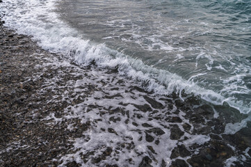 Water sea beach. Wave ocean blue. Stone texture reflection sun. Surface coast pebbles. 