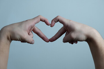 Hands form a heart shape. Worm hearts with hands on a light background