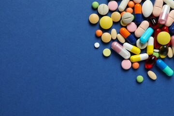 Various pills and capsules on a color background