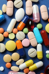 Various pills and capsules on a color background