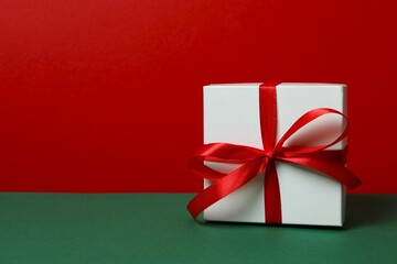 Beautiful gift box tied with bow on color background 