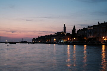 Fototapeta premium Sunset panorama view of old town Rovinj cityscape. Colored sky and streetlights reflecting in the water.