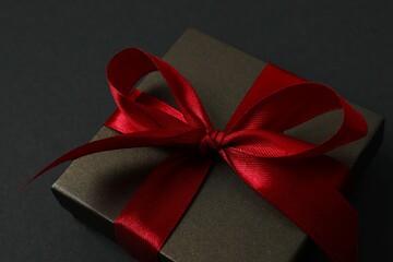 Beautiful gift box tied with bow on black background 