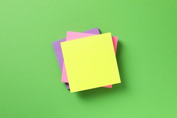 Top view of stack of colorful sticky notes on green background