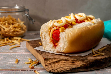 Brazilian Hot dog on green plate with corn and mayonnaise, crispy fries on background